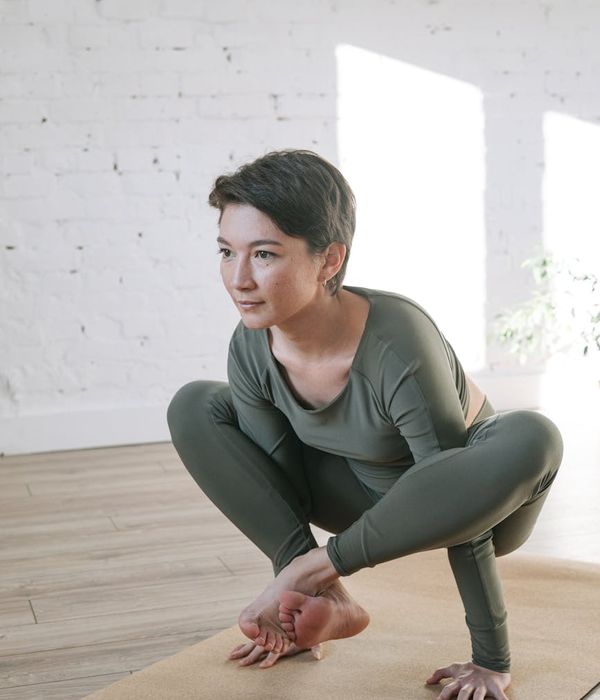 Woman in a calm, balanced pose, feeling serene in a bright, modern room.